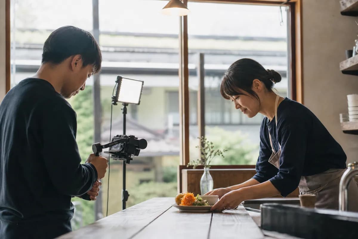カフェで料理を撮影するスタッフと店主のイメージ